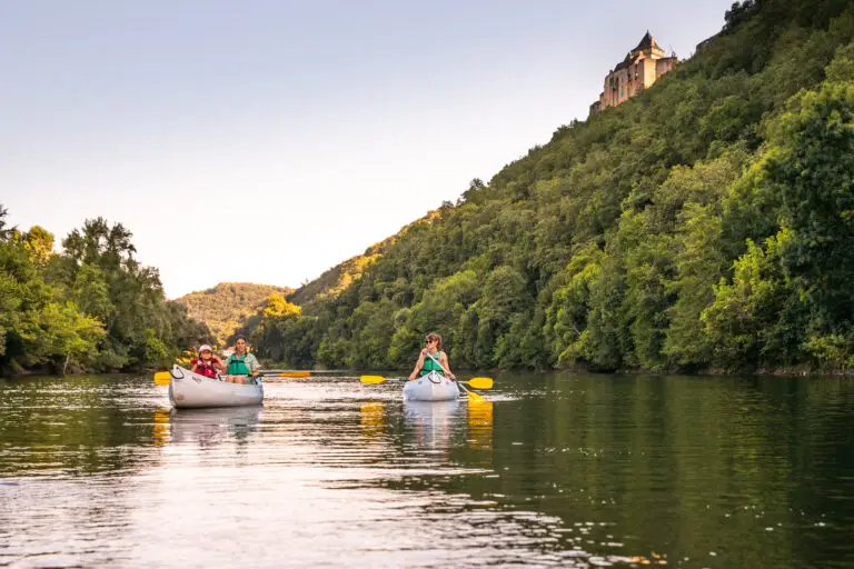 Deux canoës sur la Dordogne au lever du jour, devant le château de Castelnaud